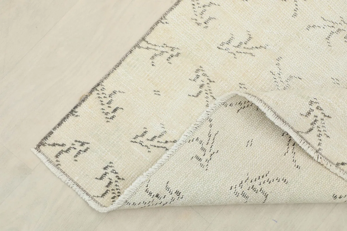 Corner of the rug folded to reveal the cotton foundation and the reverse side of the hand-knotted wool pile.