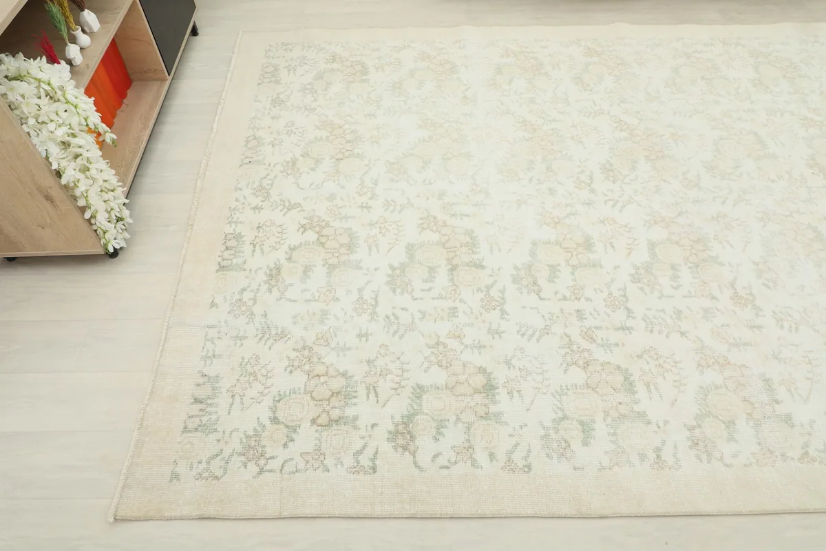 Another angle view of the ivory and tan floral vintage rug, showing part of the subtle design and border.