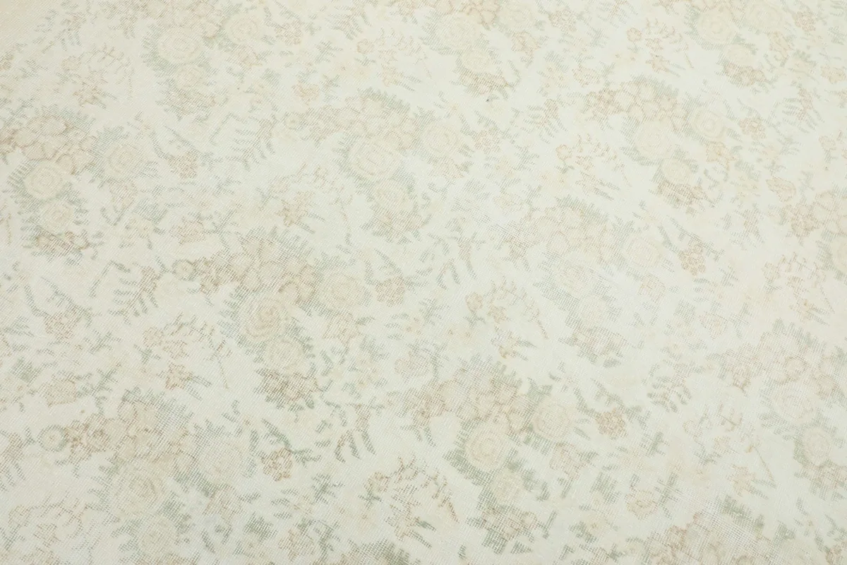 Detailed close-up of the ivory field and faded tan and olive floral patterns on the vintage Anatolian rug.