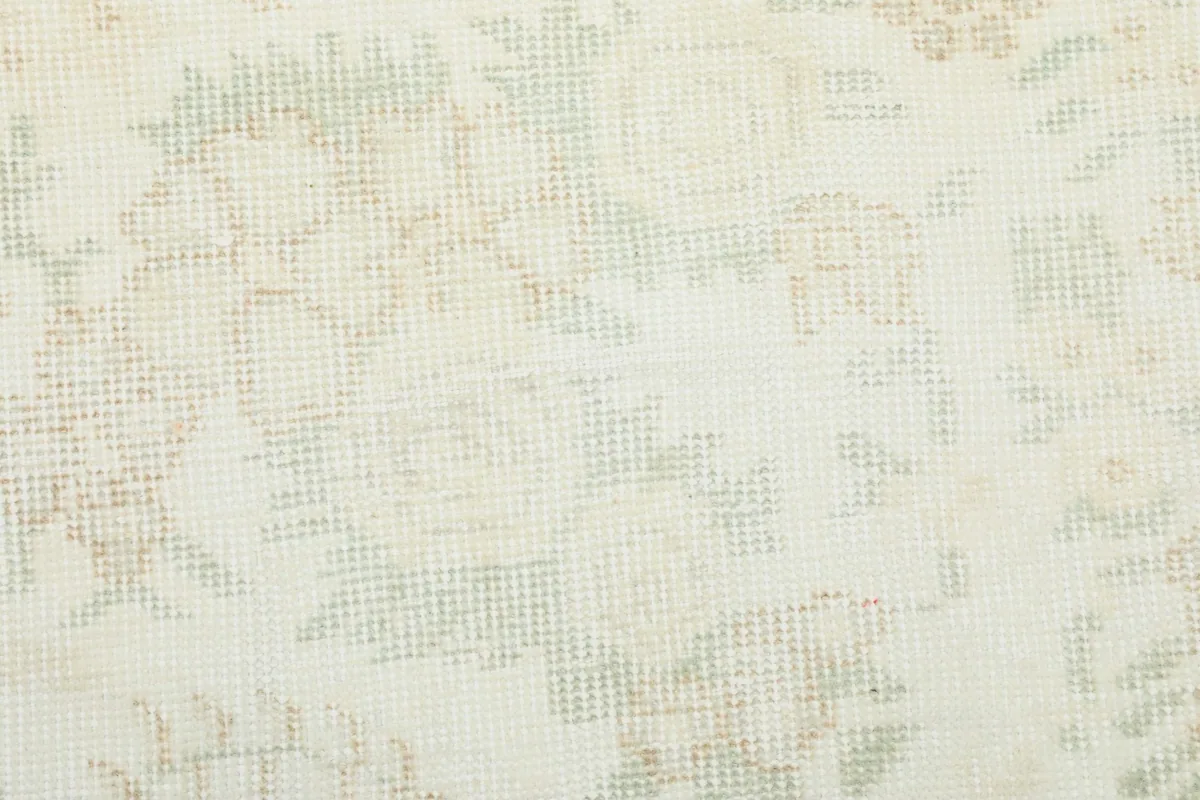 Close-up showing the low pile texture and the subtle, distressed appearance of the floral motifs.