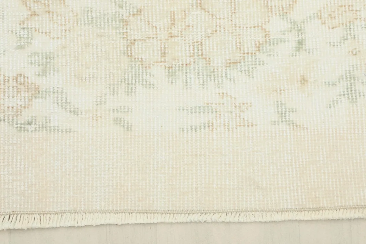 Detail of the rug's edge, showcasing the subtle border design and short, natural fringes.