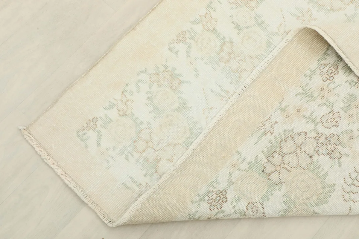 View of the vintage rug folded back to reveal the back of the hand-knotted wool pile on a cotton foundation.