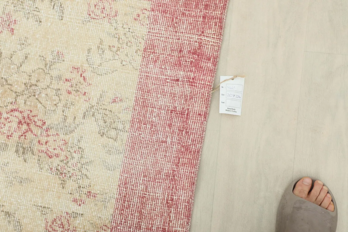 Top-down view of the rug's border next to a foot for scale, showing its texture