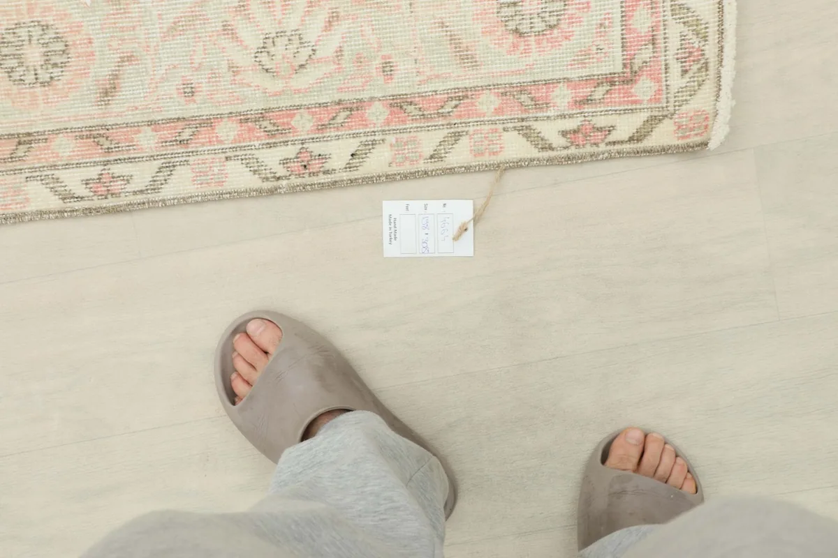 Feet in slippers next to the rug, indicating scale and showing the texture of the pile.