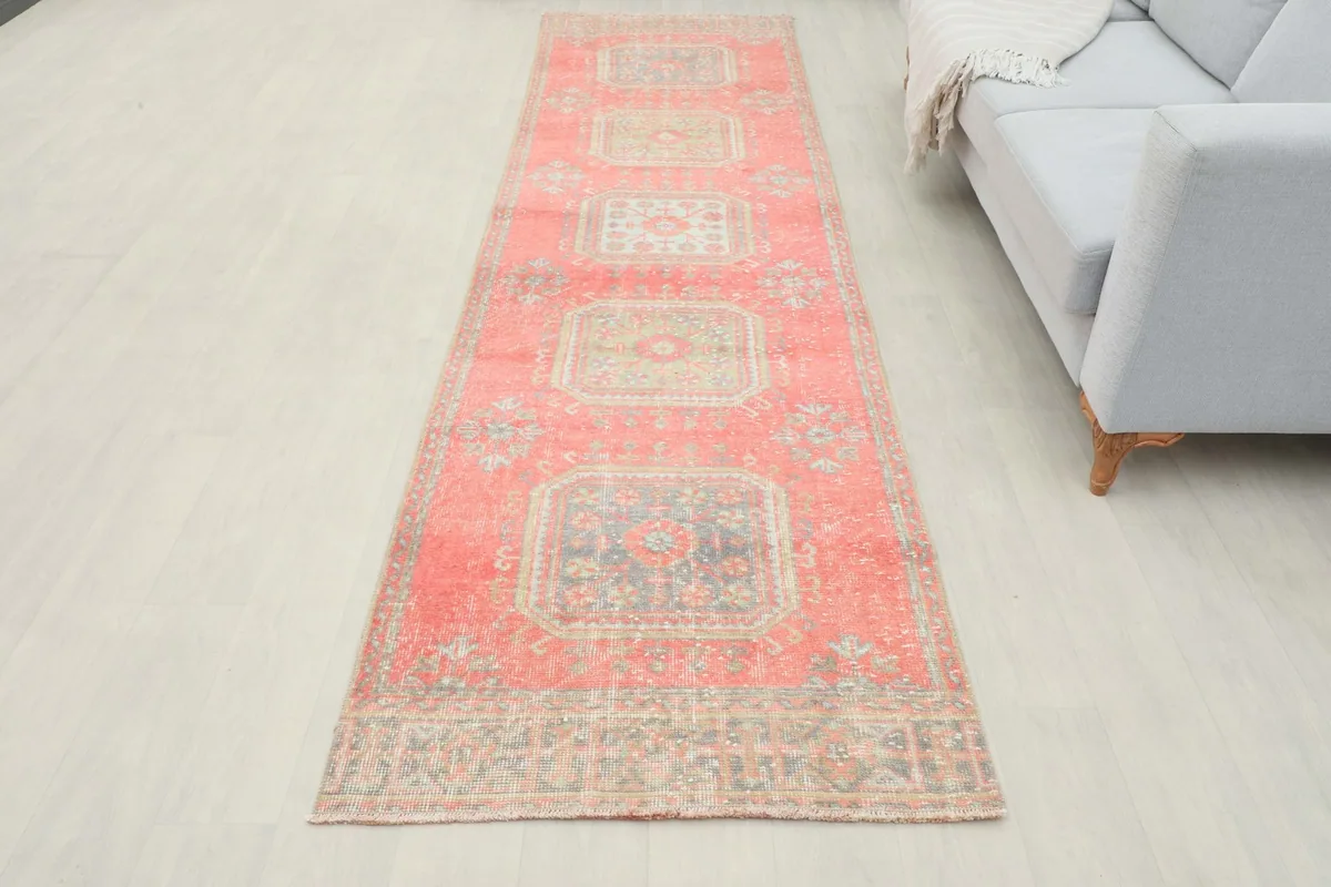 Full overhead view of the rose runner rug in a room setting, next to a gray sofa.