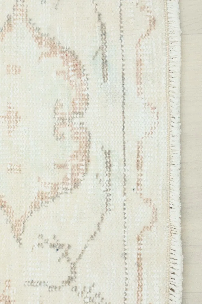 Close-up view of the rug's border and fringe, revealing the hand-knotted wool pile.
