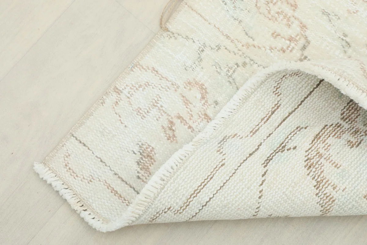 Folded corner showing the cotton foundation and the reverse side of the hand-knotted rug.