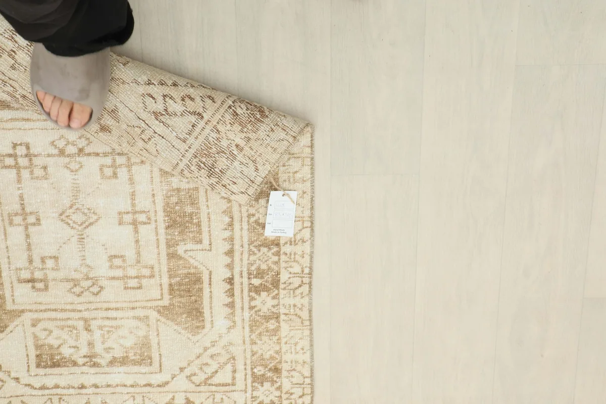 Overhead view of a foot on the rug next to a RugsKilim tag, indicating scale and authenticity.