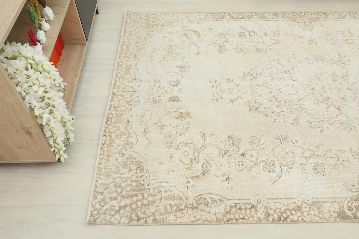 Overhead angle of the rug showing a corner and part of the main field with faded patterns
