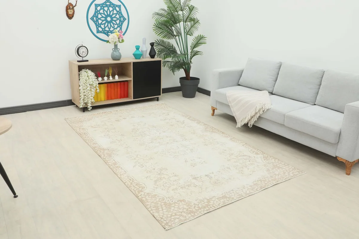 Cream and tan vintage rug placed in a living room setting with a light gray sofa
