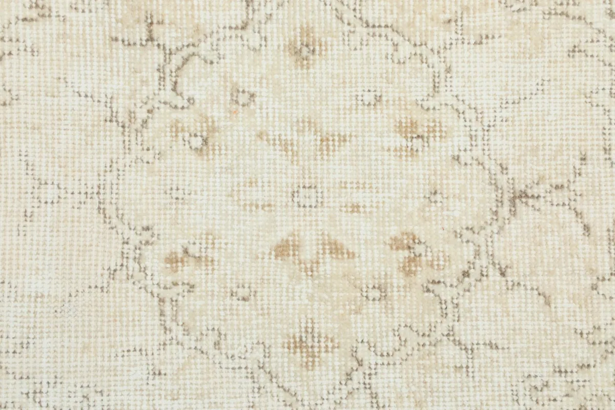 Close-up of the faded geometric and floral patterns within the rug's design