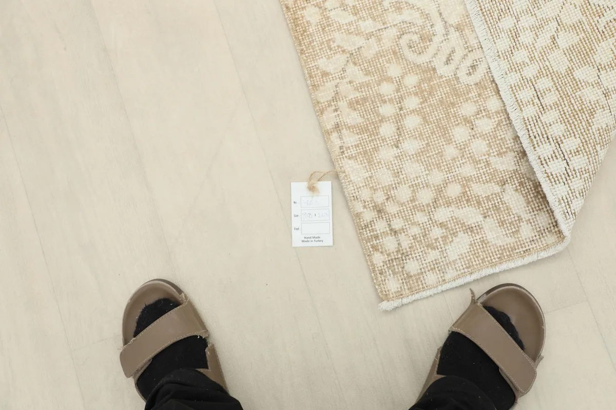 Overhead view of a person's feet next to the rug and a product tag, indicating scale