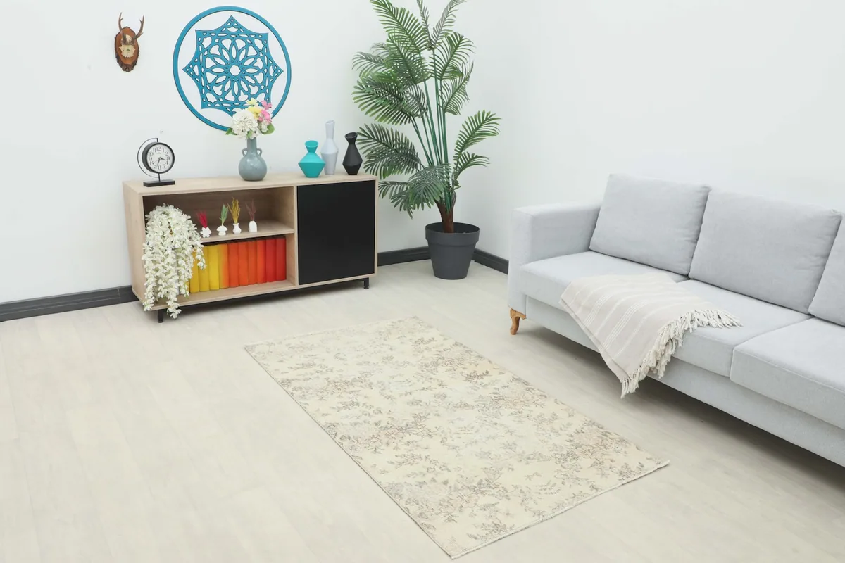 Ivory floral rug placed in a living room setting with a light gray sofa