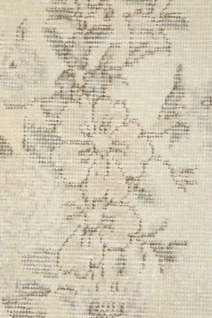 Macro detail of the hand-knotted wool pile and faded floral pattern