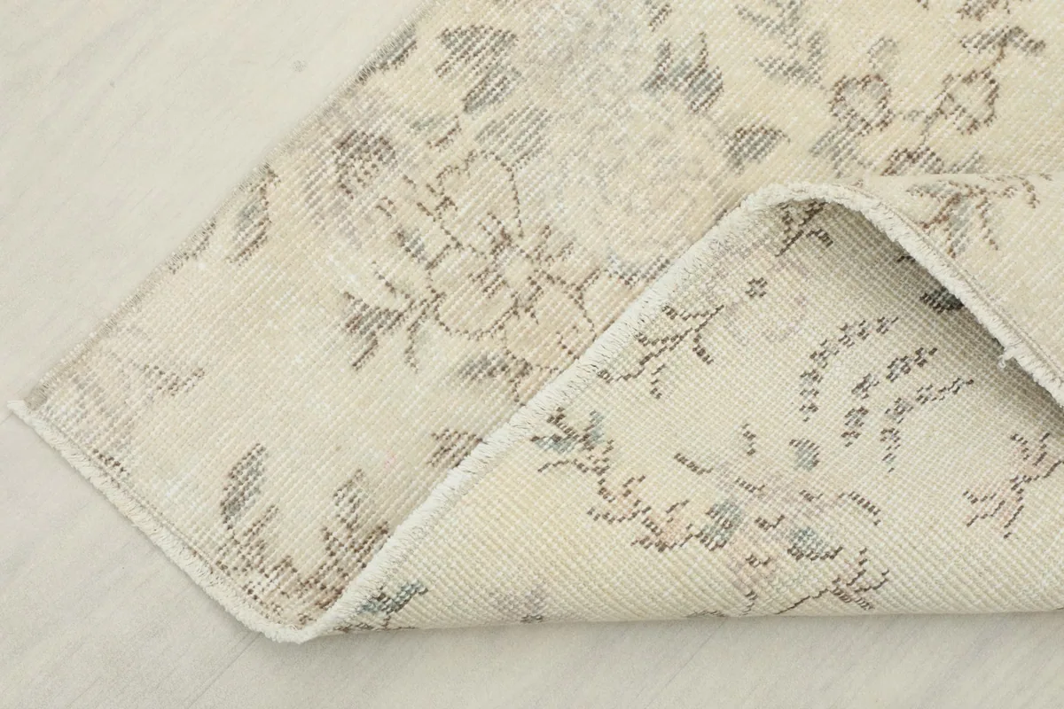 Corner of the rug folded back, revealing the cotton foundation and hand-knotted construction