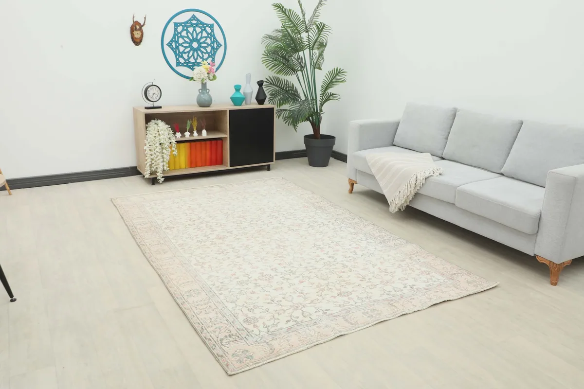 Ivory floral rug in a modern living room setting with a light gray sofa and wooden cabinet
