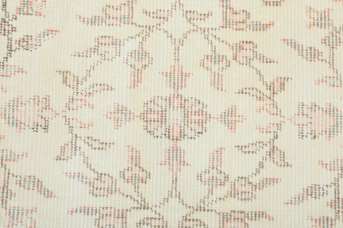 Close-up of the hand-knotted texture and faded rose and green colors in the floral design