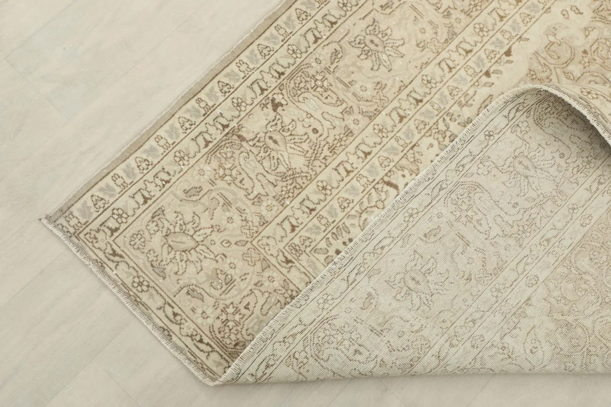 Corner of the rug folded back to reveal the cotton foundation and reverse side of the hand-knots