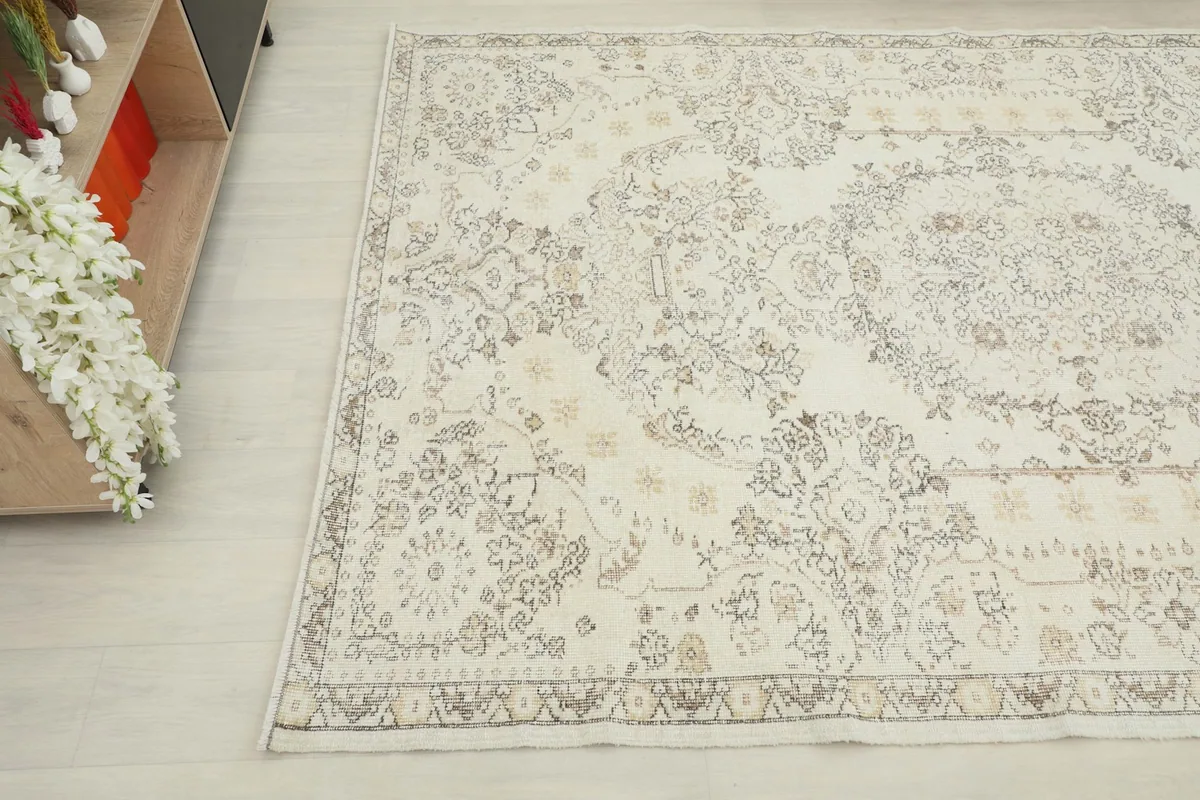 Angled view of the vintage wool rug, showing its soft cream tones and subtle patterns