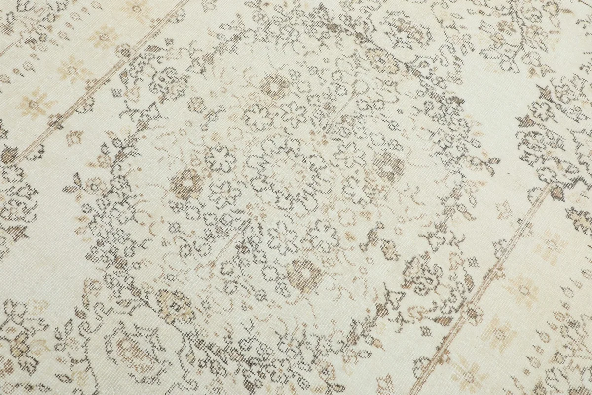 Close-up detail of the central medallion design in gray and tan on the cream rug