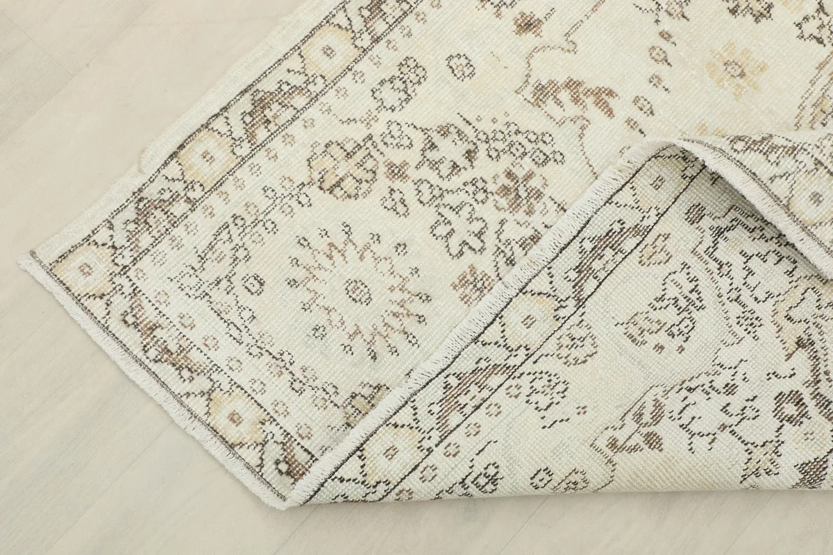 Corner of the rug folded back, revealing the cotton foundation and hand-knotted construction