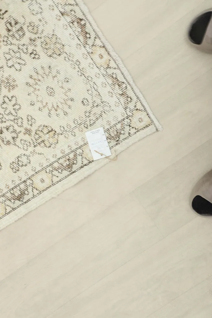 Corner of the rug with a size tag, providing scale reference against a light floor