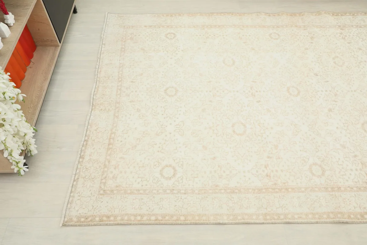 Upper corner view of the vintage rug, capturing the interaction of its cream field with the tan border.