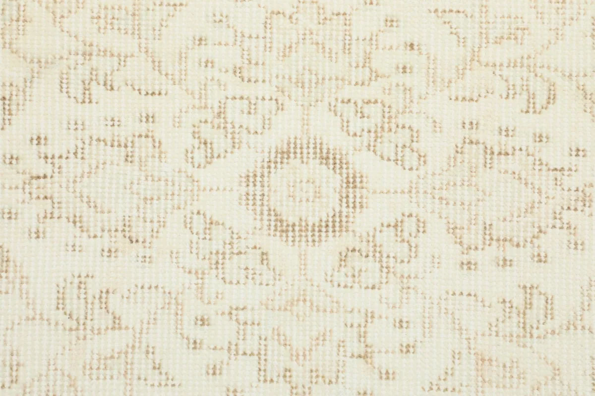 Detailed close-up of the hand-knotted wool pile, showing the cream and tan colors and subtle pattern.