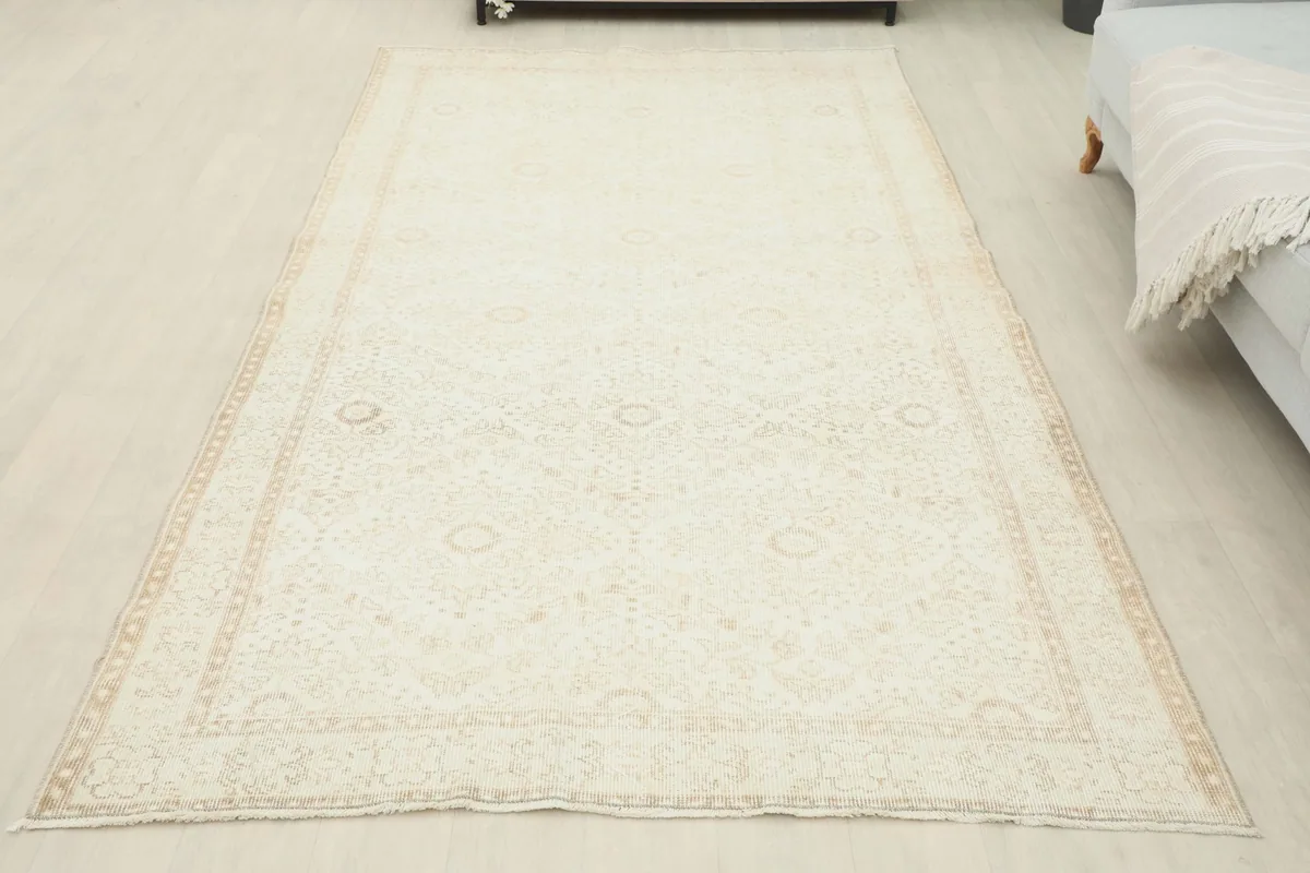 Full overhead shot of the cream vintage rug in a room, offering a complete perspective of its design.