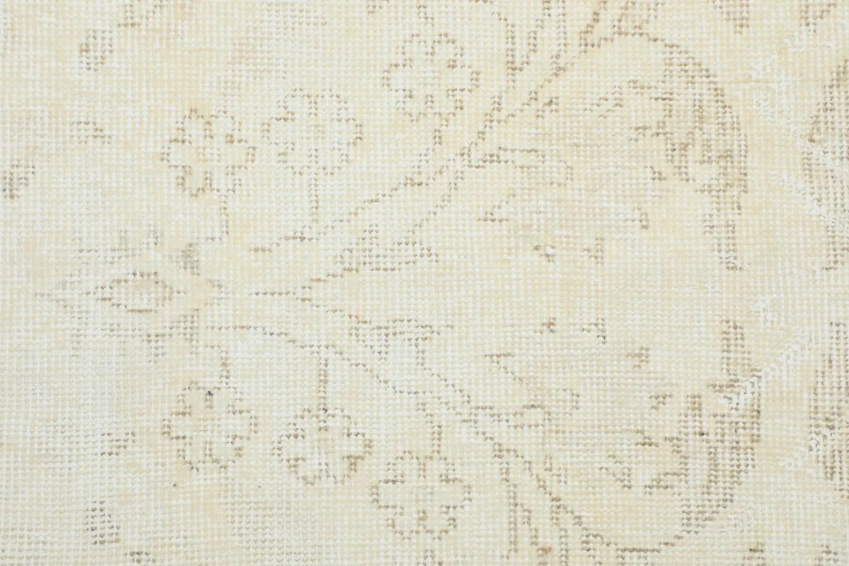 Close-up of the hand-knotted wool pile, revealing the intricate beige floral motifs