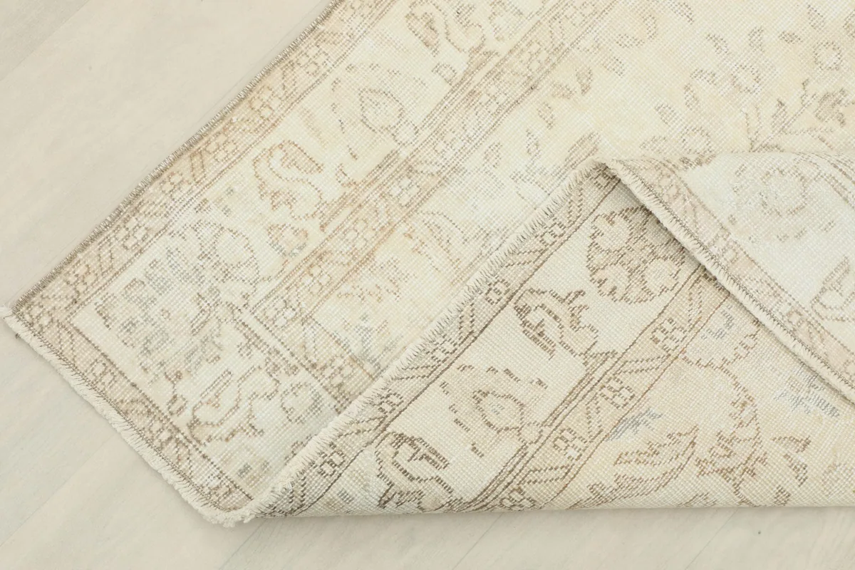 Corner of the rug folded back, showcasing the reverse side of the hand-knotted cotton foundation