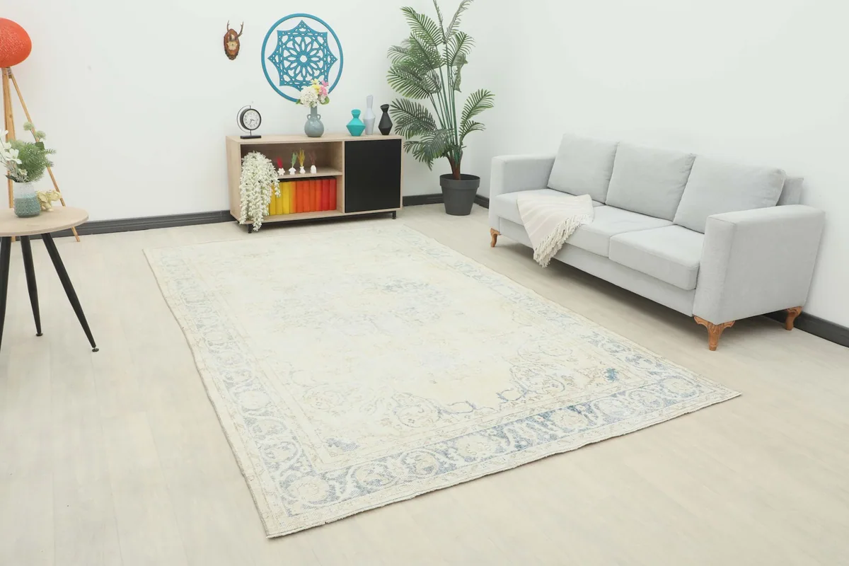 Ivory and blue vintage rug displayed in a living room setting with a light gray sofa.
