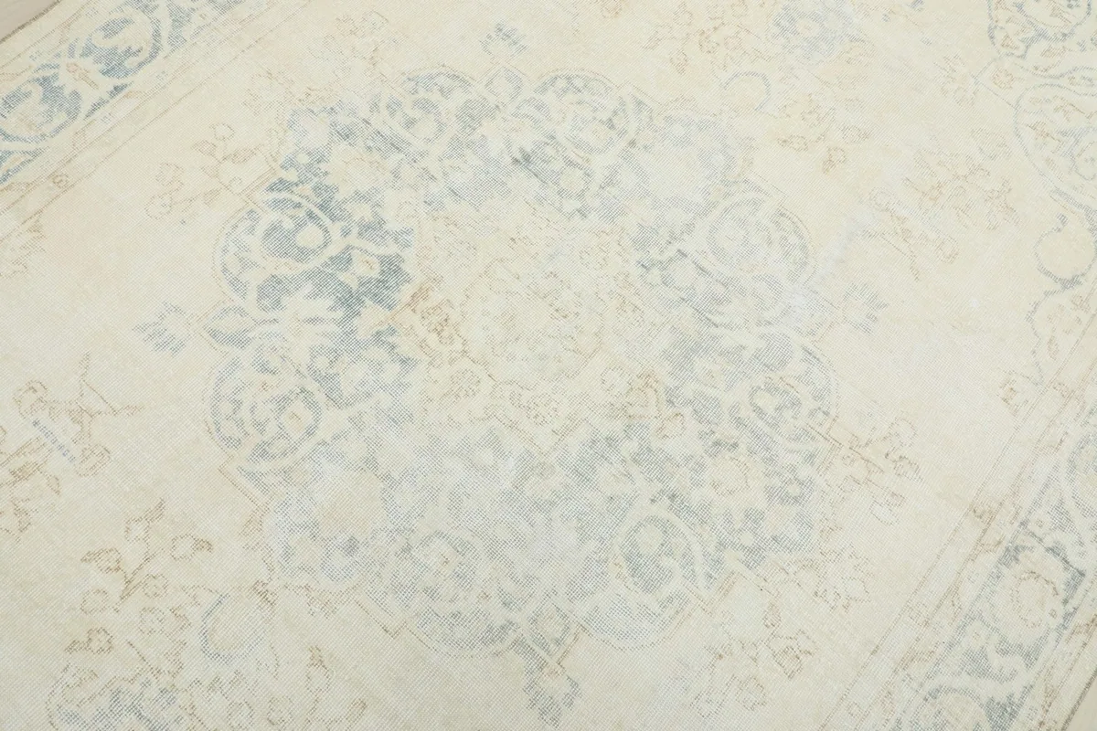 Detail view of the central medallion and surrounding patterns, showing faded blue tones.