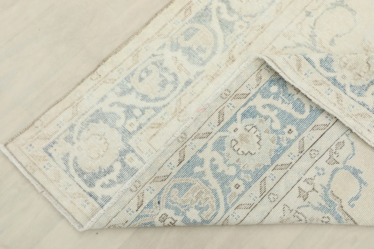 Folded corner of the rug, revealing the woven cotton foundation and reverse side.