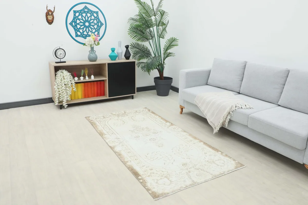 Ivory and brown vintage rug placed in a modern living room setting next to a gray sofa.