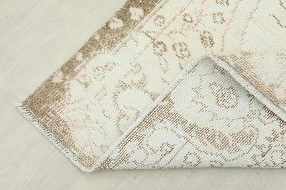 Corner of the rug folded to reveal the cotton foundation and the reverse side of the knotting.