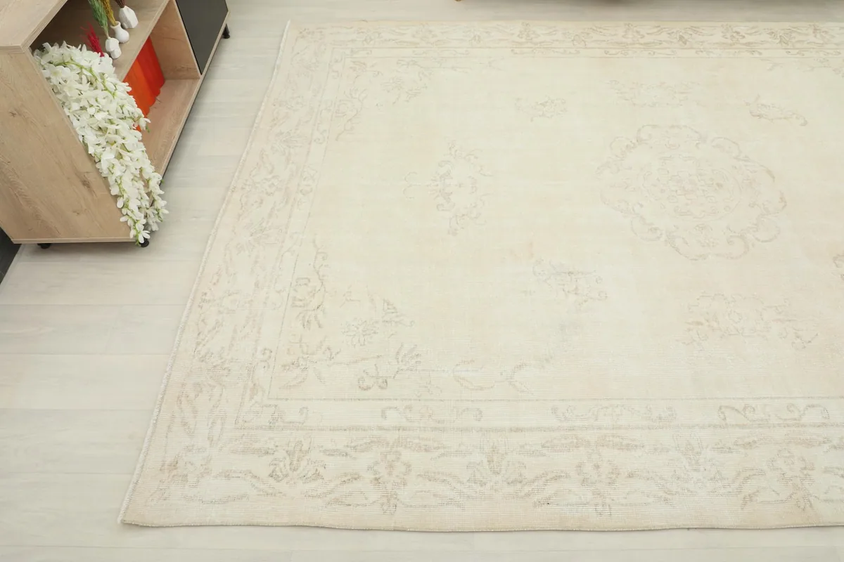 Overhead angle view of the ivory rug's surface, showing subtle beige floral border details