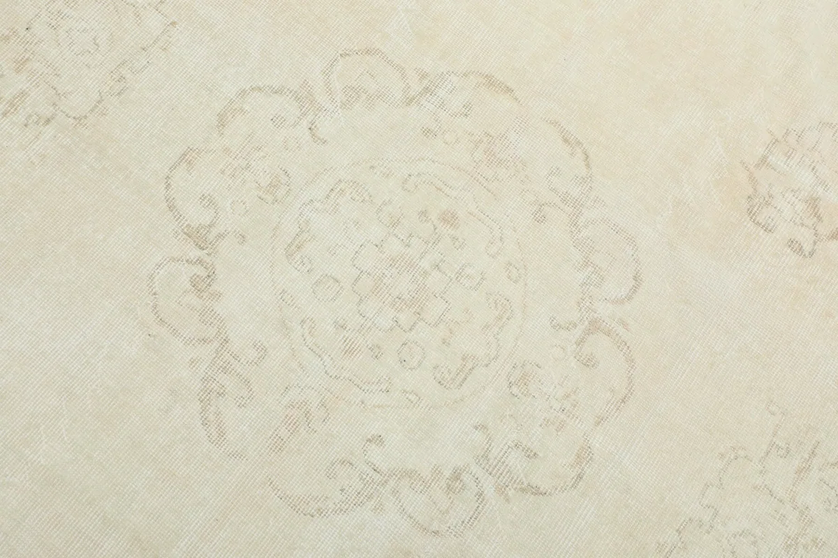Detailed view of the central medallion motif on the ivory rug, showing its faded design