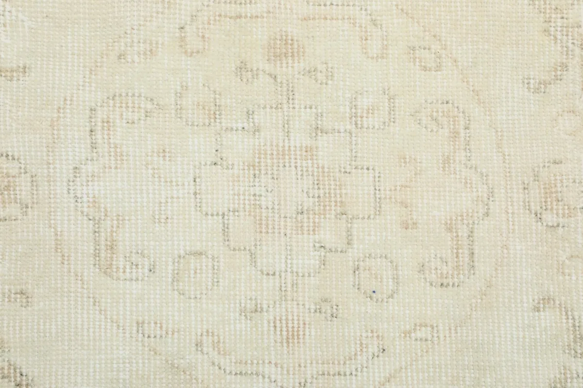 Close-up of the low wool pile and hand-knotted texture of the ivory vintage rug