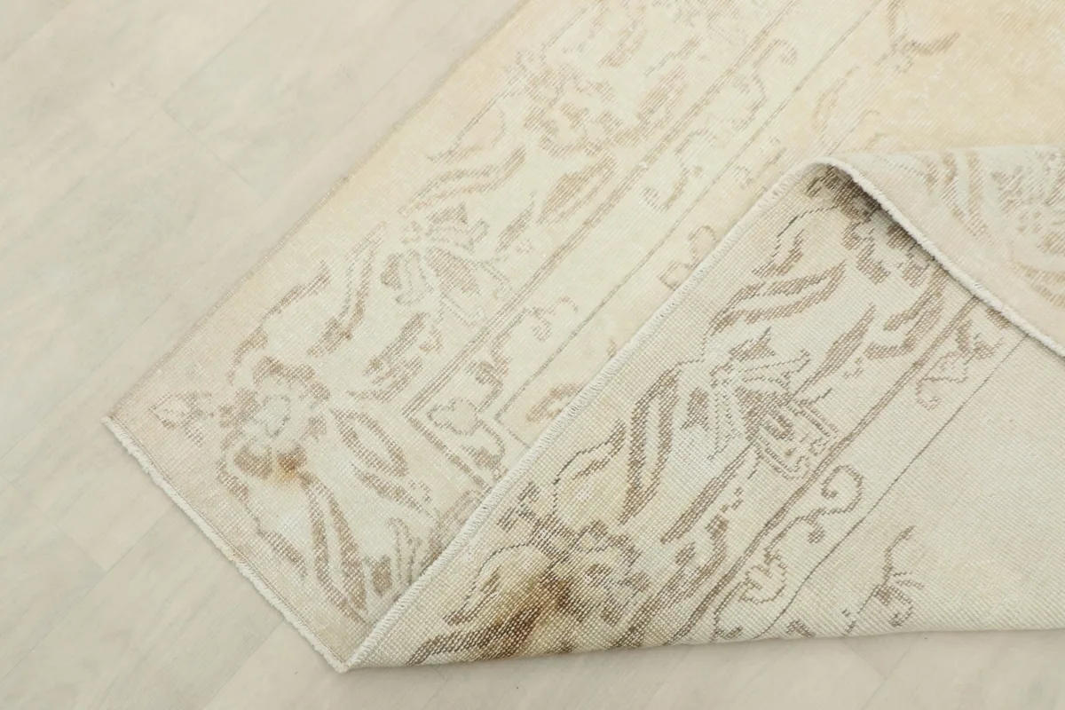 Corner of the rug folded back, revealing the cotton foundation and the reverse of the design