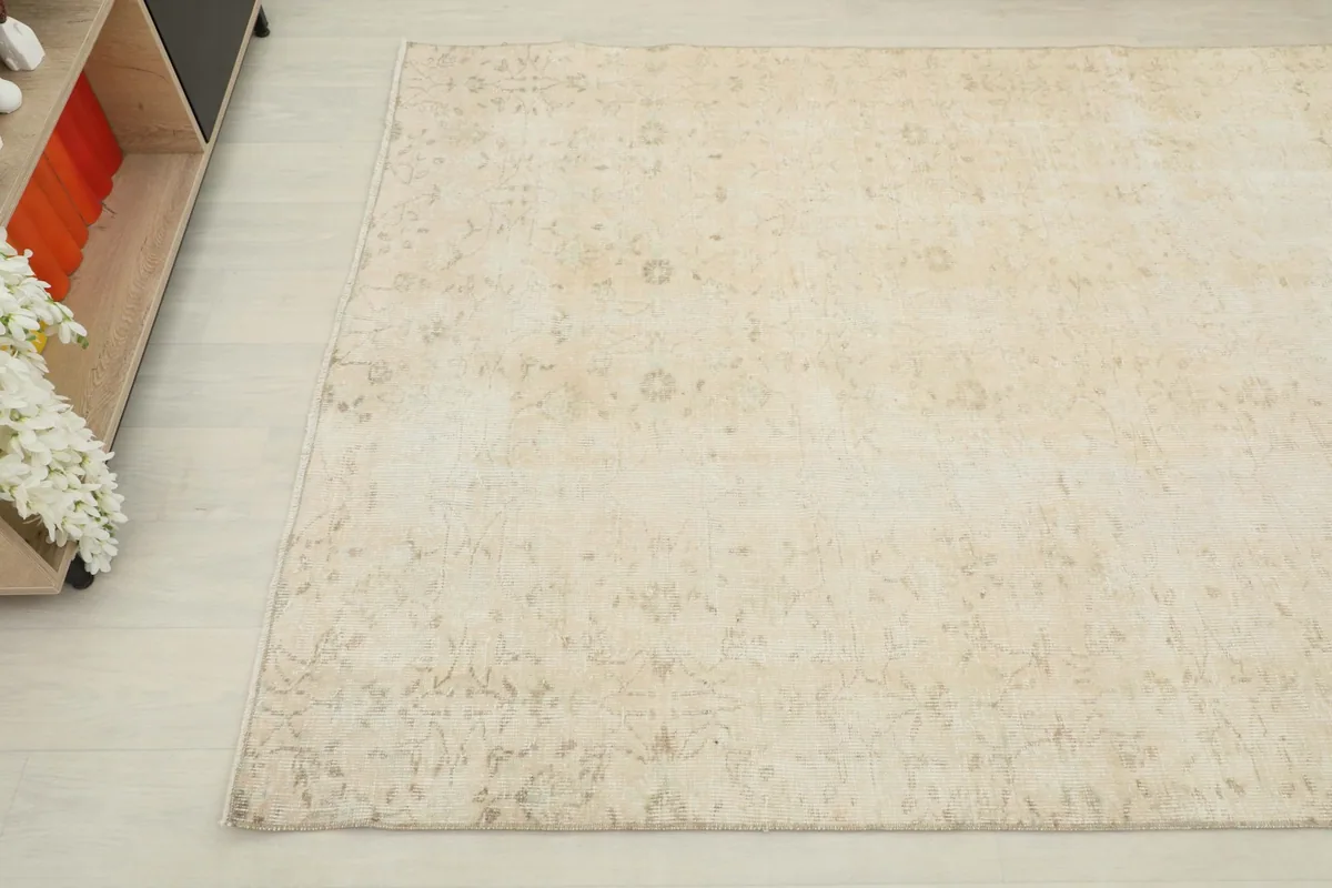 Overhead angle shot of the beige vintage rug, showing its natural variations and light patina.
