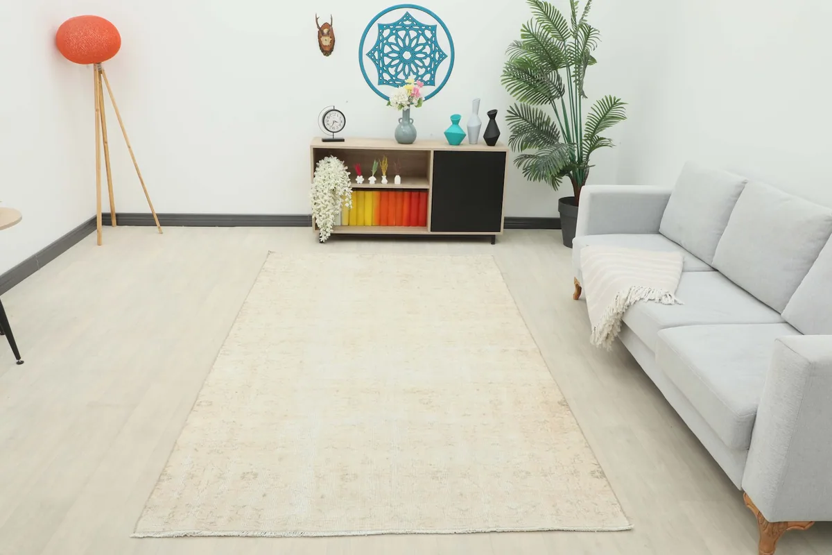 Wide shot of the 5'1" x 8'10" vintage beige rug placed in a room, offering a sense of its scale.