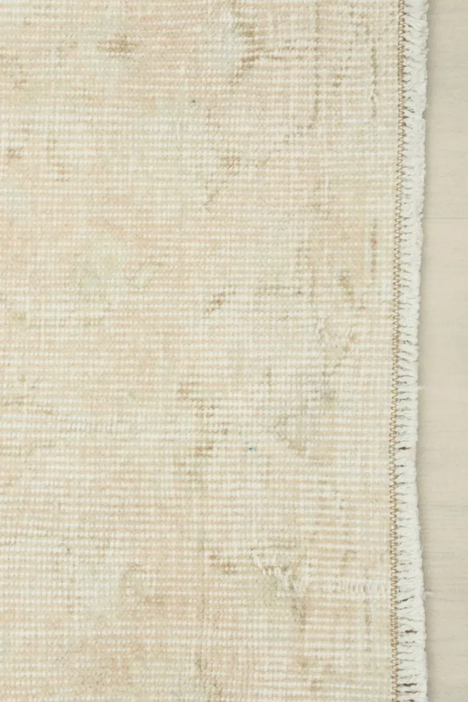 Detail of the rug's edge, showing the tightly woven cotton foundation and short, neat fringes.