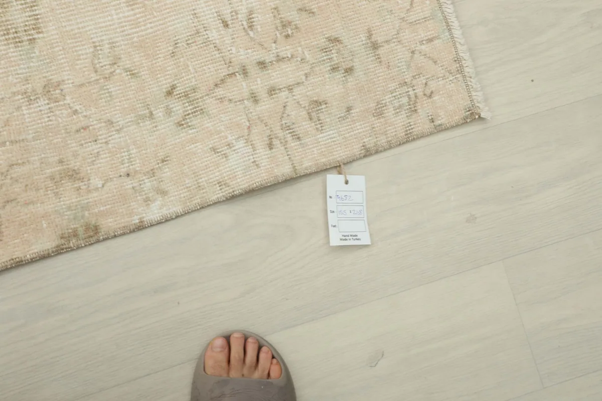Rug tag detail next to a foot, indicating the rug's authenticity and origin.