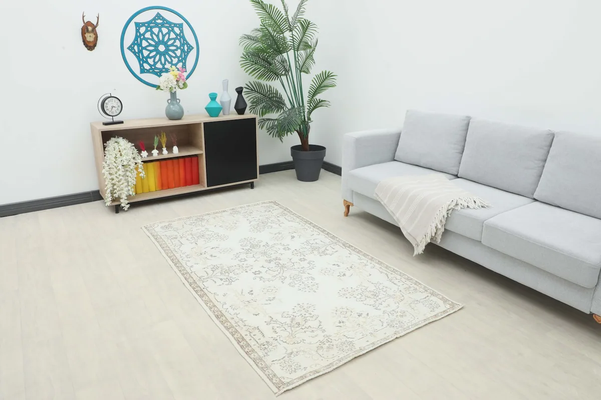 Ivory vintage rug in a living room setting with a light gray sofa and wooden furniture