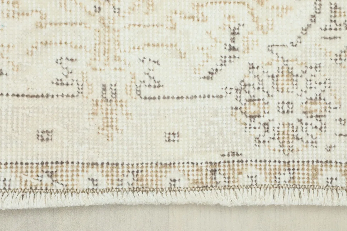 View of the rug's short, natural wool fringe and the edge of the border