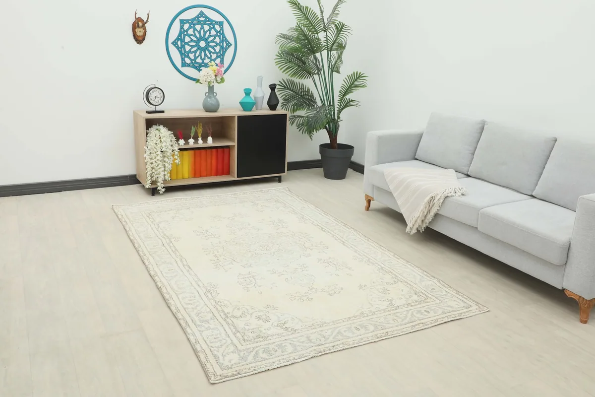 Ivory and gray vintage rug placed in a modern living room setting with a light gray sofa