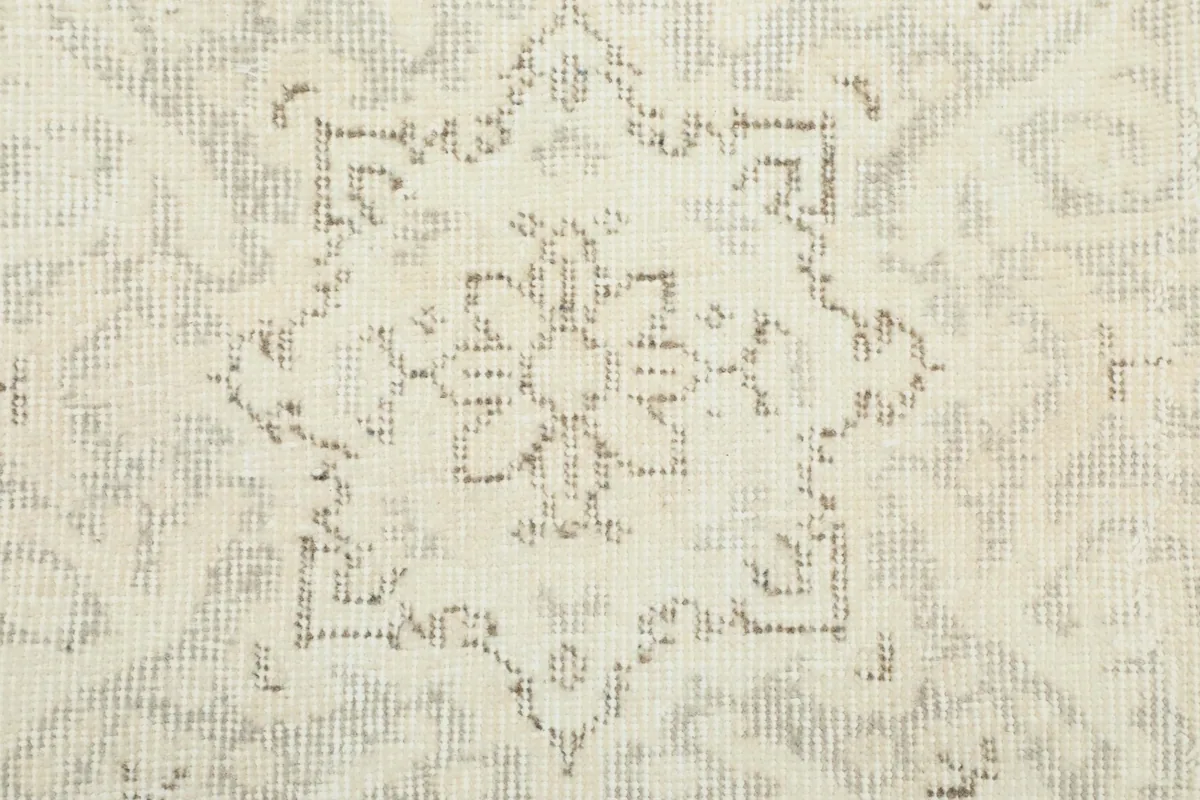 Close-up of a faded star-like motif within the rug's pattern, showing wool texture