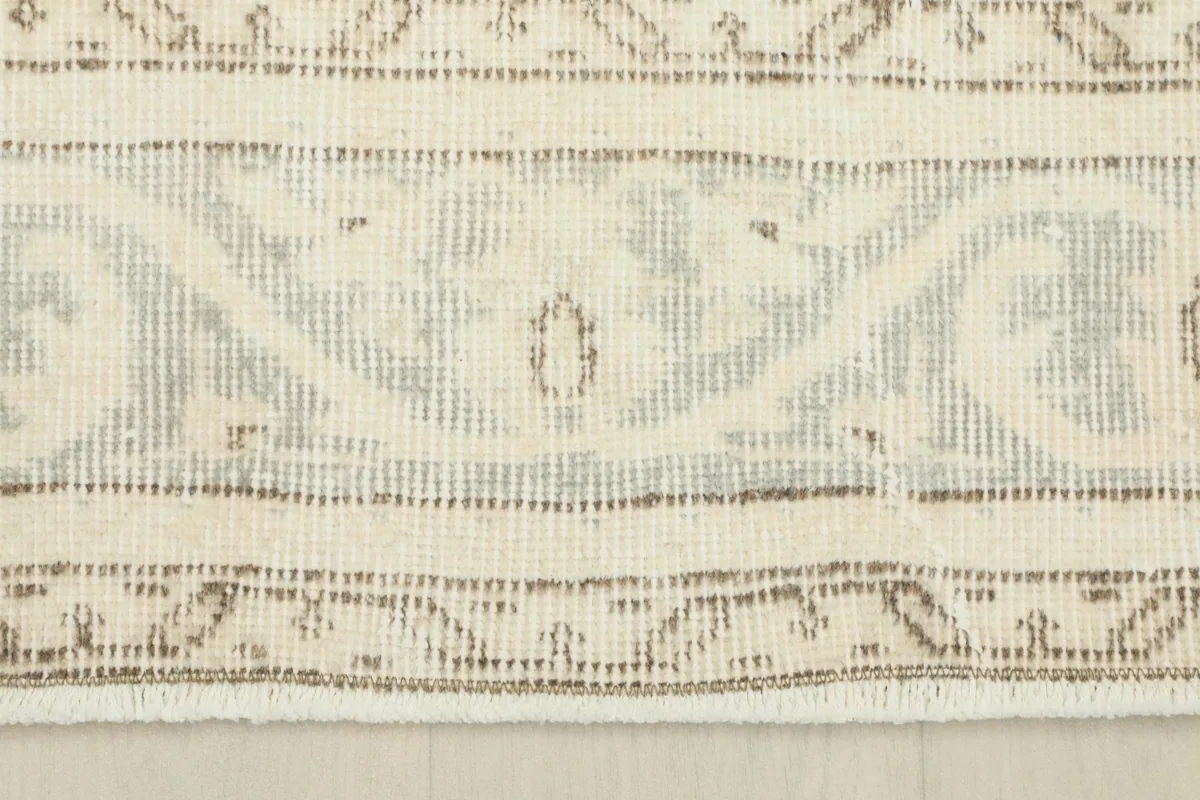 Detailed view of the rug's intricate geometric border pattern and muted tones