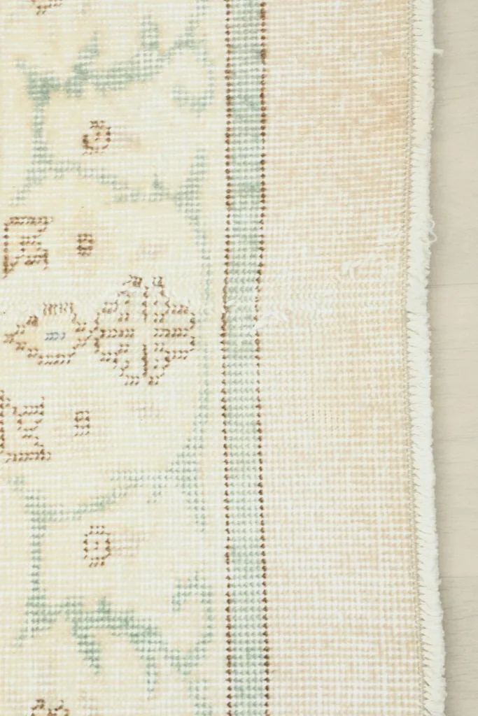 View of the rug's edge, showing the hand-knotted wool pile and cotton foundation